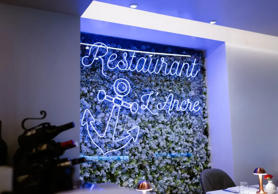 Le mur floral et son enseigne néon « Restaurant L'Ancre » dans la salle